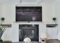 TV mounted between built-in cabinetry beside a fireplace