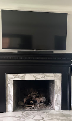 TV and soundbar mounted above a black marble fireplace