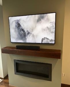 TV mounted on a floating mantel above marble tile